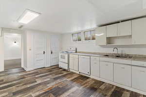 Kitchen featuring white appliances, light countertops, white cabinetry, and dark wood-type flooring
