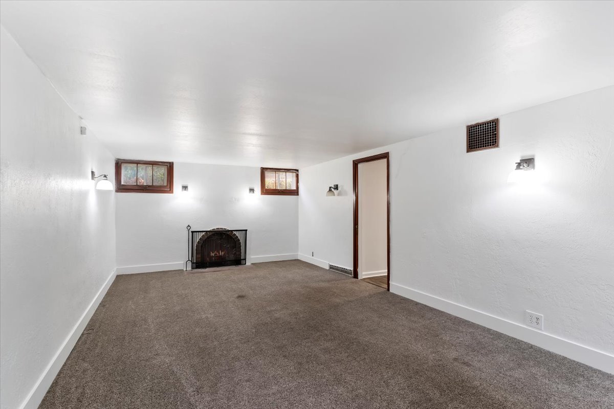 Unfurnished living room with dark colored carpet and a fireplace with flush hearth