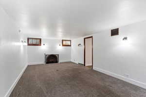 Unfurnished living room with dark colored carpet and a fireplace with flush hearth
