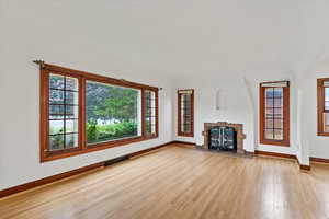 Unfurnished living room featuring a tiled fireplace, light wood-type flooring, and healthy amount of natural light