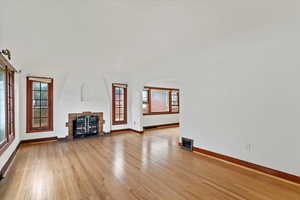 Unfurnished living room with light wood-style flooring, a tile fireplace, and healthy amount of natural light