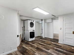 Laundry room with estacked washer and dryer and dark wood-style flooring