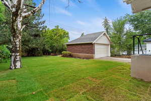 View of green lawn with an outdoor structure and a garage