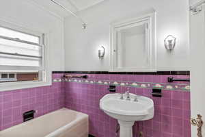 Full bath featuring tile walls, a bath, and a wainscoted wall