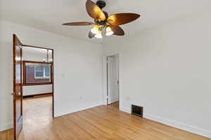 Unfurnished room with light wood-style floors, a chandelier, and a ceiling fan