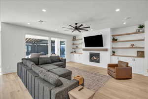 Living area with a ceiling fan, light wood finished floors, a brick fireplace, and recessed lighting
