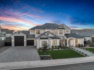 View of front of house featuring decorative driveway, stone siding, a standing seam roof, an attached garage, and a metal roof