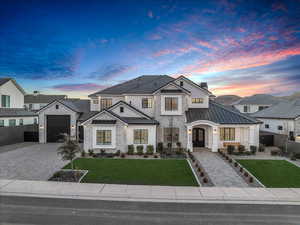 View of front facade featuring stone siding, a standing seam roof, decorative driveway, a metal roof, and stucco siding