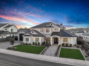 View of front of house with a standing seam roof, stone siding, french doors, decorative driveway, and a chimney