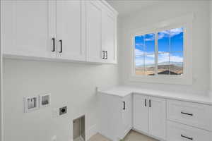 Laundry area with electric dryer hookup, cabinet space, and washer hookup