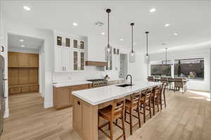 Kitchen with light wood-style floors, a kitchen island with sink, a breakfast bar, recessed lighting, and light countertops