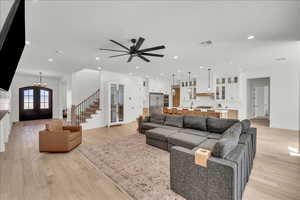 Living area featuring light wood-style floors, stairs, recessed lighting, french doors, and a chandelier
