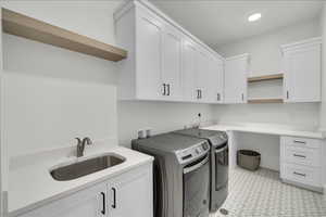 Laundry room with washing machine and dryer, cabinet space, and light floors