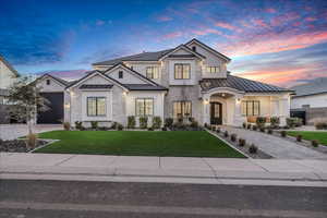Modern inspired farmhouse featuring a standing seam roof, driveway, stone siding, and a front yard