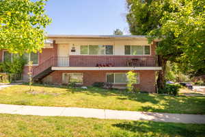 View of front of home featuring a front lawn, brick siding, and stairs