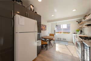 Kitchen featuring freestanding refrigerator, stainless steel range with gas stovetop, light wood-style flooring, open shelves, and recessed lighting
