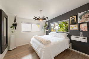 Bedroom featuring wood finished floors, concrete block wall, and brick wall