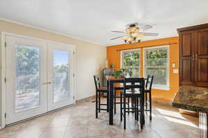 Dining space featuring french doors, ceiling fan, crown molding, a textured ceiling, and light tile patterned floors