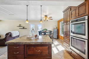 Kitchen featuring stainless steel double oven, plenty of natural light, ornamental molding, pendant lighting, and a kitchen island