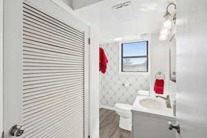 Bathroom with vanity, wood finished floors, and wallpapered walls