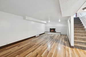 Unfurnished living room featuring wood finished floors, stairs, and a fireplace
