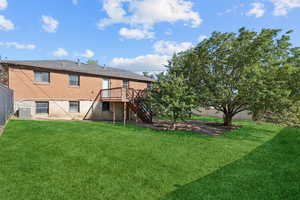 Rear view of property with stairs, a fenced backyard, a wooden deck, and brick siding
