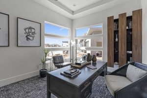 Office area featuring dark carpet and baseboards