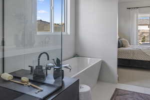 Ensuite bathroom featuring a bath, vanity, and tile patterned flooring