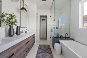 Bathroom with a shower stall, double vanity, a soaking tub, and tile patterned flooring