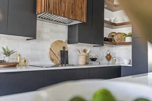 Kitchen view of open shelves, modern cabinets, wall chimney exhaust hood, tasteful backsplash, and light countertops