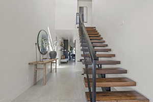 Stairs with a towering ceiling and tile patterned floors