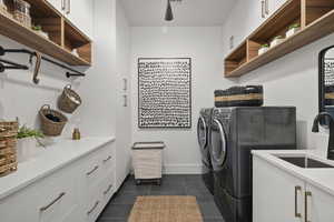 Laundry area featuring separate washer and dryer, cabinet space, and dark tile patterned floors