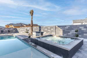 View of swimming pool featuring an in-ground hot tub and a fenced backyard