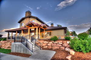 View of front of house with a chimney, a porch, board and batten siding, and stone siding