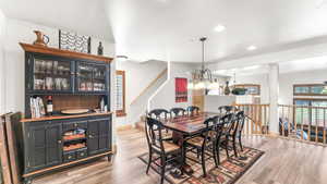 Dining area featuring light wood-style floors, a chandelier, a bar, and recessed lighting