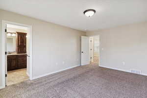 Unfurnished bedroom featuring light colored carpet and connected bathroom
