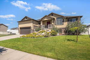 View of front of house with stucco siding, concrete driveway, a front yard, and brick siding
