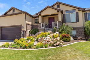 View of front facade featuring brick siding, stucco siding, an attached garage, and a front yard