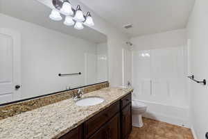 Bathroom featuring vanity, washtub / shower combination, and stone finish floors