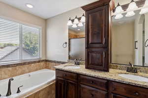Bathroom featuring double vanity, a garden tub, and a stall shower
