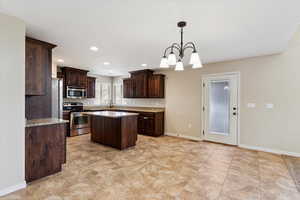 Kitchen featuring stainless steel appliances, dark brown cabinetry, a chandelier, a center island, and pendant lighting