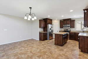 Kitchen with stainless steel appliances, a center island, dark brown cabinetry, a chandelier, and recessed lighting