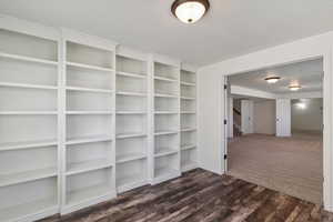 Empty room with stairs, dark wood-style flooring, and a textured ceiling