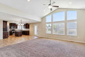 Unfurnished living room with light colored carpet, recessed lighting, ceiling fan, a chandelier, and high vaulted ceiling
