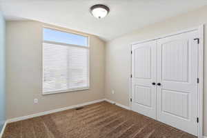 Unfurnished bedroom featuring carpet flooring, a closet, and lofted ceiling