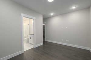 Unfurnished bedroom featuring dark wood finished floors and ensuite bathroom