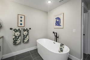 Full bathroom with a freestanding tub and dark tile patterned floors
