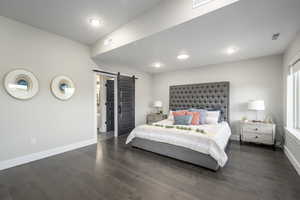Bedroom featuring a barn door and dark wood-type flooring