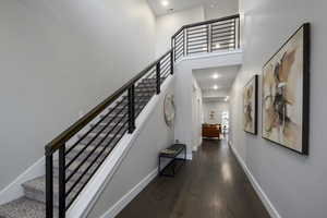 Staircase with a towering ceiling, wood-type flooring, and recessed lighting