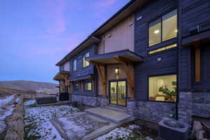 Snow covered property entrance featuring stone siding and a mountain view